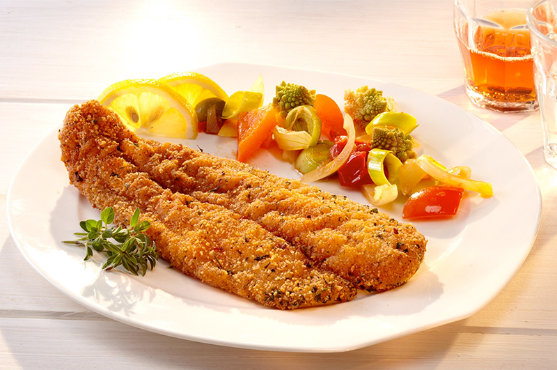 Paniertes Fleisch mit angebratenem Gemüse.