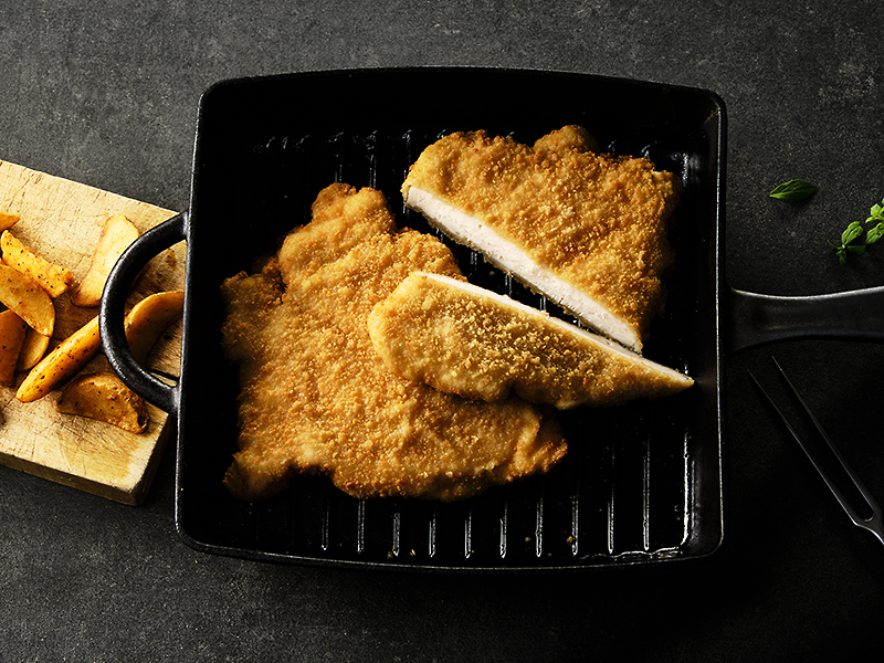 Schnitzel in einer Grillpfanne. Kartoffelwedges als Beilage.